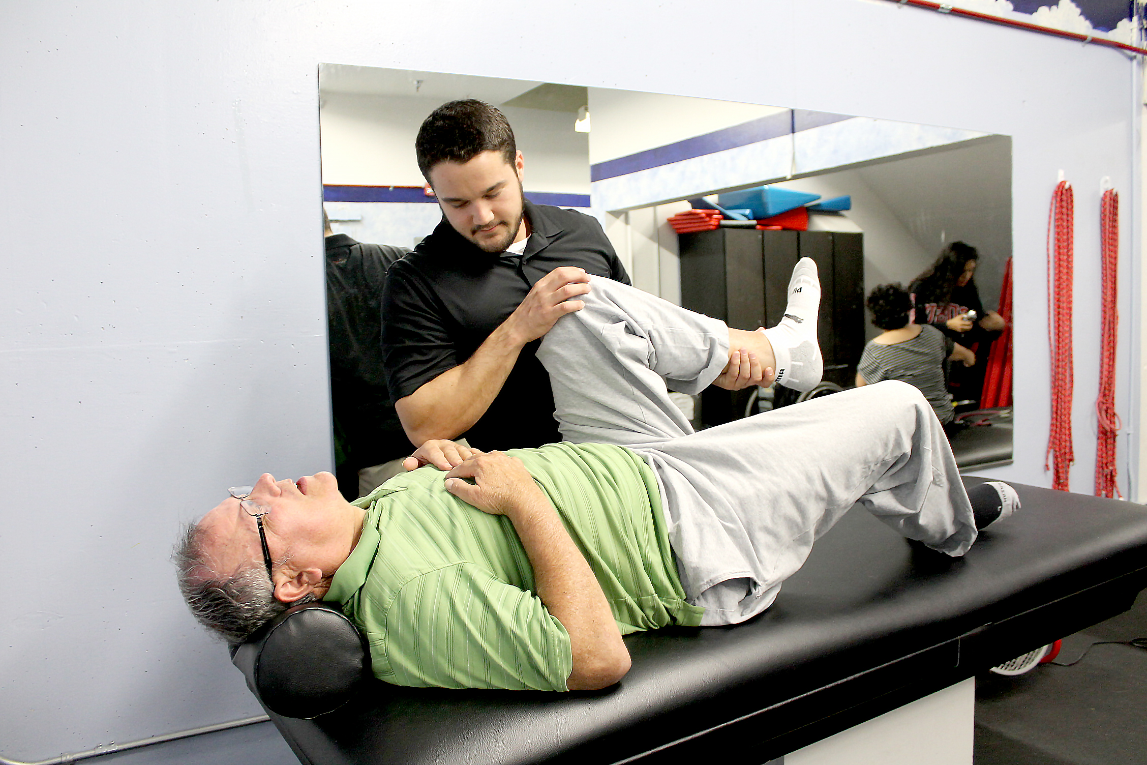 Man stretching with assistance of student