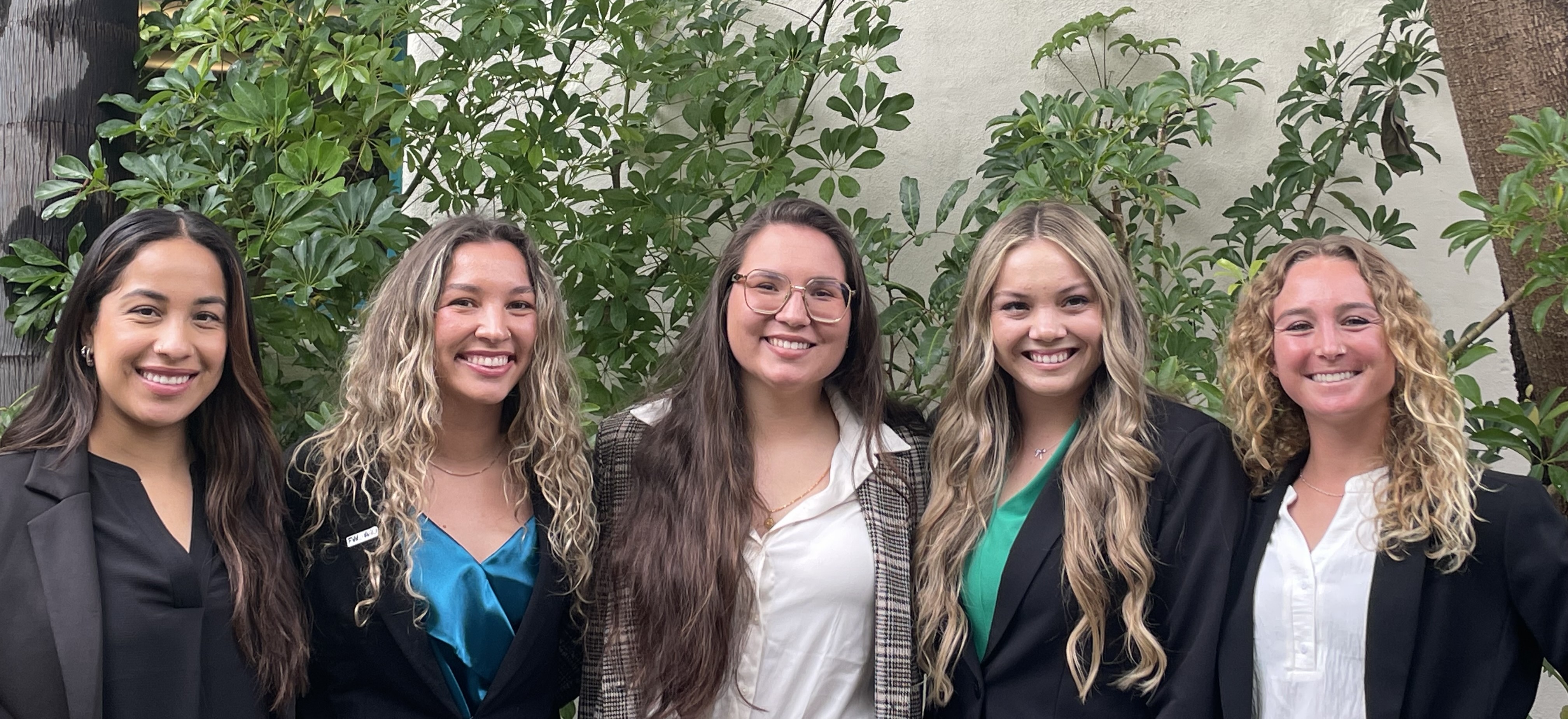 Five young females dressed professional smiling for a photo.